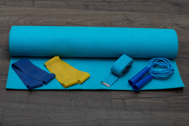Vista frontal de las cuerdas de salto, bandas elásticas de fitness y alfombra de fitness azul. Estilo de vida saludable y espacio de copia, lugar para el concepto de texto - Foto, imagen