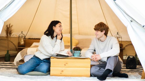 Un couple qui parle dans une tente au glamping. Forêt luxuriante autour - Photo, image