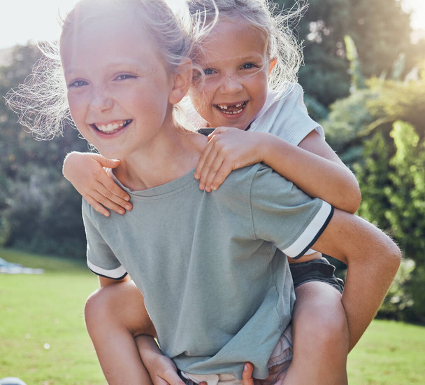 Lapset, hymyilkää ja sisko possu takaisin tyttö ulkona on leikkisä, onnellinen tai rentoutua yhdessä kesälomalle. Sisarukset, siskot ja pelaa innoissaan ruohoa, lapset pitää hauskaa ja nauttia leikkipäivästä tai pelistä. - Valokuva, kuva