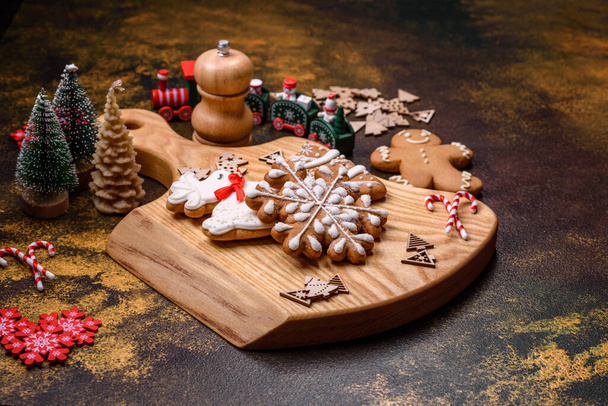 Krásný perník na hnědém keramickém talíři s vánoční ozdobou stromku na tmavém betonovém pozadí. Připravujeme se na Vánoce. - Fotografie, Obrázek