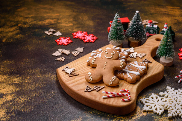 Krásný perník na hnědém keramickém talíři s vánoční ozdobou stromku na tmavém betonovém pozadí. Připravujeme se na Vánoce. - Fotografie, Obrázek