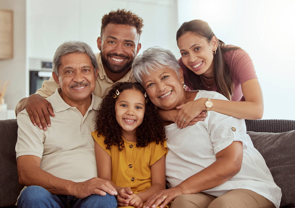 Portrait of mixed race family with child enjoying weekend in living room at home. Adorable smiling hispanic girl bonding with grandparents, mother and father. Happy couples and child sitting together. - Photo, Image