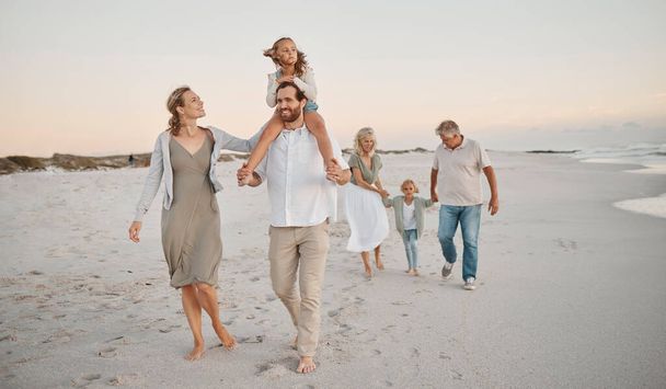 Family walking on the beach together. Happy family bonding on holiday by the sea. Grandparents strolling on the beach with grandchildren. Caucasian family on the beach together on holiday. - Photo, Image