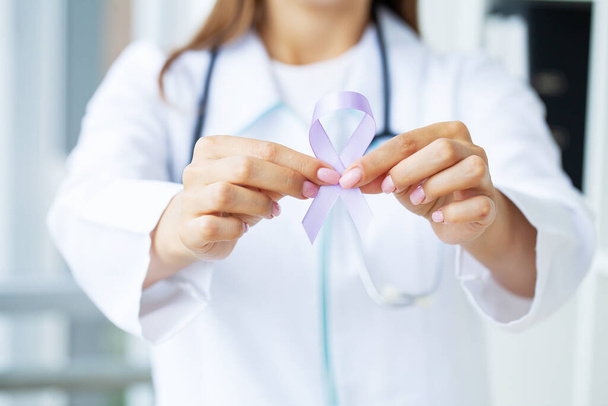 Žena lékař bílá uniforma držet fialovou stuhu na ruce symbol vědomí rakoviny slinivky břišní. - Fotografie, Obrázek