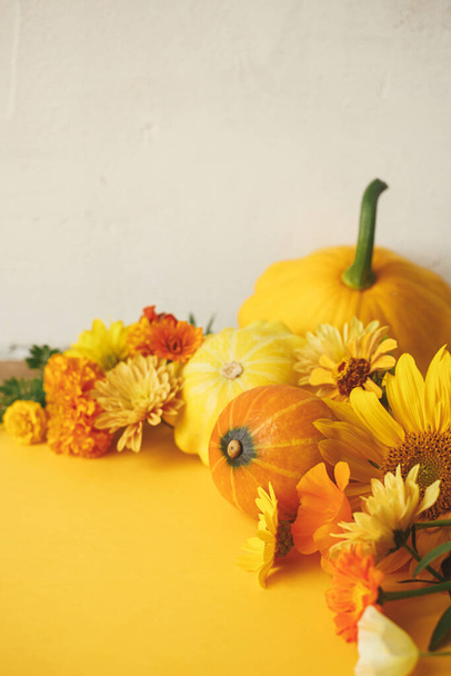 Happy Thanksgiving! Colorful autumn flowers, pumpkins, pattypan squashes on yellow paper against rustic background. Creative autumn still life. Seasons greeting card template with space for text - Fotó, kép