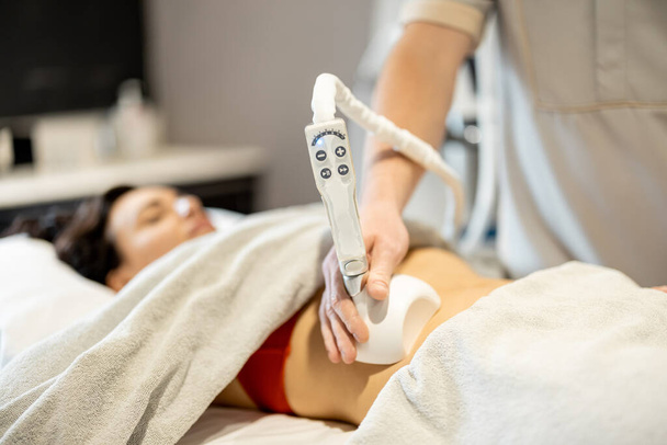 Woman receiving vacuum roller massage for her belly at medical beauty centre. Anti-cellulite and lymphatic drainage massage procedure - Foto, Imagen