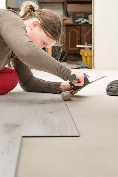 Žena instaluje křemennou vinylovou podlahu, montáž na plochý povrch křemenné vinylové podlahy, opravy v domě. - Fotografie, Obrázek