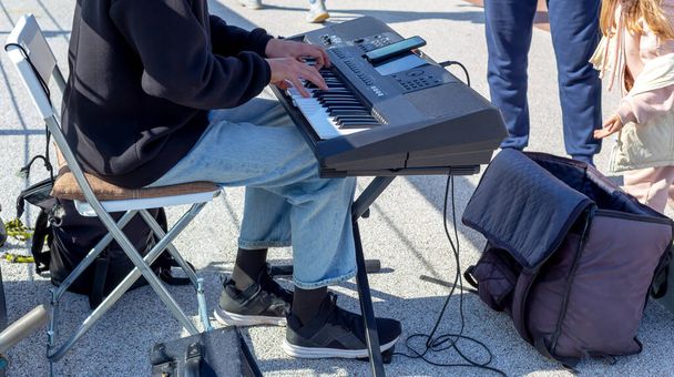Bir sokak müzisyeni synthesizer çalıyor. Küçük bir kız çantaya para atıyor. Yaşam biçimi - Fotoğraf, Görsel