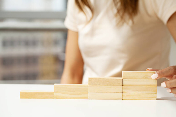 Закрыть Женская рука укладки деревянных блоков как ступеньки - Фото, изображение