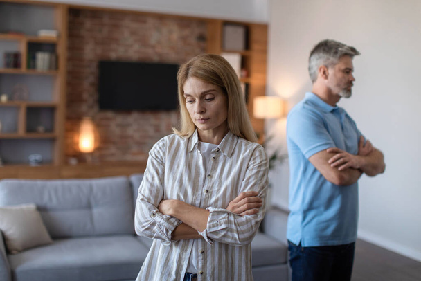 Unhappy sad middle aged european husband ignores offended wife after scandal and think about divorce in living room interior. Stress and emotions, relationship problems at home due covid-19 pandemic - Foto, Bild