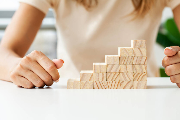 Hand arranging wood cube stacking as step stair - Photo, Image