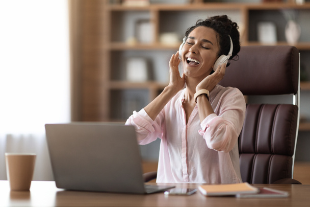 職場の概念におけるストレス緩和。音楽や歌を聴く幸せな若い実業家の女性,女性は、コンピュータの前でワークデスクに座って,無線ヘッドセットを使用して,コピースペース - 写真・画像