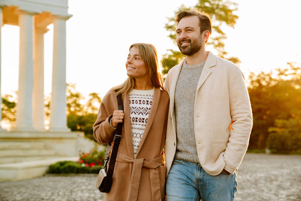 秋の公園を歩いている間、白いロマンチックなカップルの笑顔と抱擁 - 写真・画像