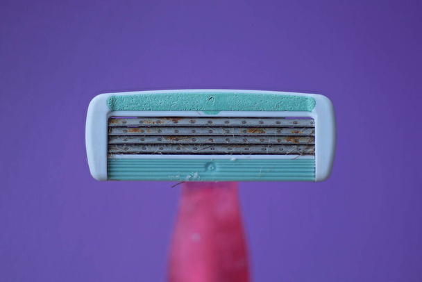 una vieja navaja de afeitar verde gris oxidado sobre un fondo lila - Foto, imagen