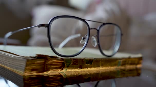 Aika ja tieto käsite, Silmälasit tai silmälasit pidetään päälle todella vanha revitty ja osittain vaurioitunut uskonnollinen Raamattu kirja. Extreme makro lähikuva laukaus vanha vuosikerta kirja. - Materiaali, video