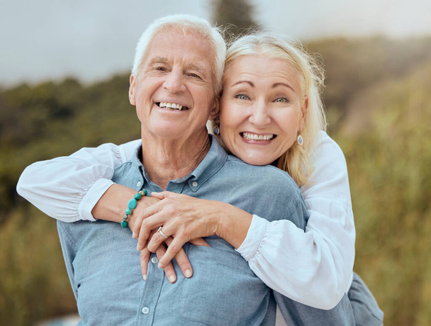 A happy mature caucasian couple enjoying fresh air on vacation at the beach. Smiling retired couple getting a cardio workout while being playful and having fun together on a romantic date. - Foto, Imagen