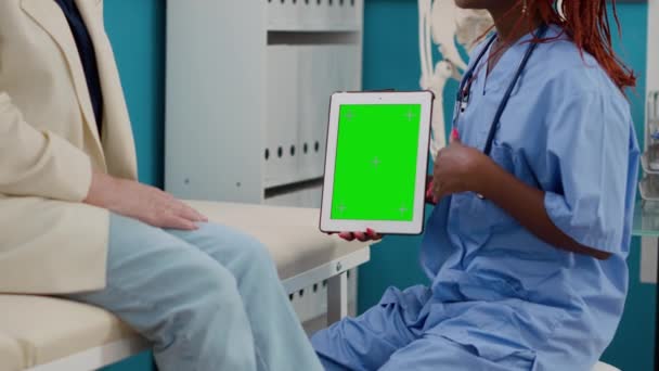 Медична медсестра і пацієнт, дивлячись на зелений колір на планшеті, мають призначення в кабінеті. Фахівець і літня жінка, що аналізує порожній дисплей хромати з ізольованою копійкою і шаблоном макету
. - Кадри, відео