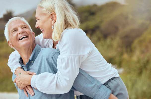 A happy mature caucasian couple enjoying fresh air on vacation at the beach. Smiling retired couple getting a cardio workout while being playful and having fun together on a romantic date. - Photo, Image