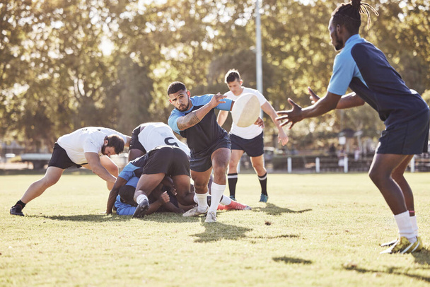 Mixed race rugby player making a pass to an african american teammate during a match outside on a field. Young male athlete passing to his team after winning a contested scrum. Attack on the offensiv. - 写真・画像