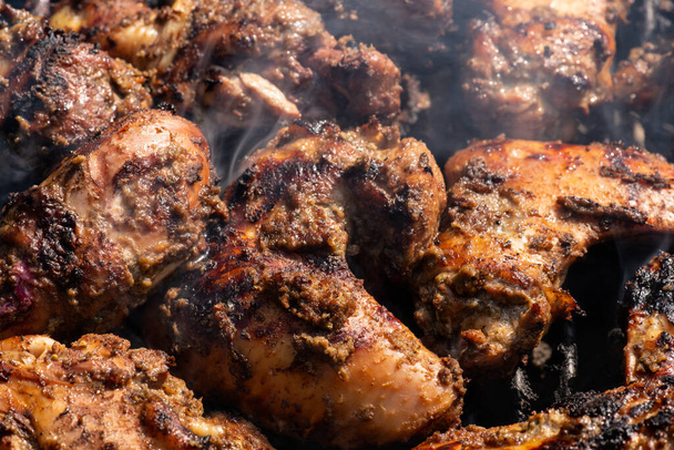 Grillen traditioneller jamaikanischer Würze jerk chicken mit über Holzkohlefeuer. - Foto, Bild