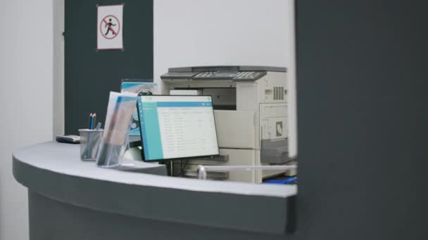 Hospital reception counter with medical appointments on computer to help patients with healthcare insurance. Empty registration desk used to give support and fill in checkup papers. - Πλάνα, βίντεο