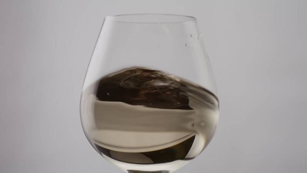 Arany bor fröccsenő klasszikus üveg serleget szuper lassított felvétel közelről. Luxus pezsgő örvénylik elegáns borosüveg fehér alapon. Friss almabor integetett átlátszó pohárban. Parti koncepció. - Fotó, kép