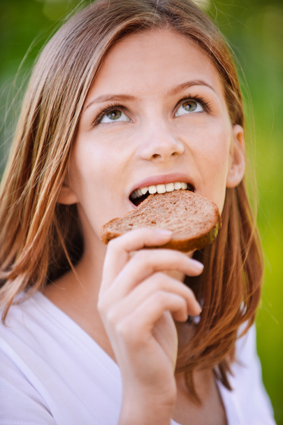 Portrait of beautiful young woman eating bread - Photo, Image
