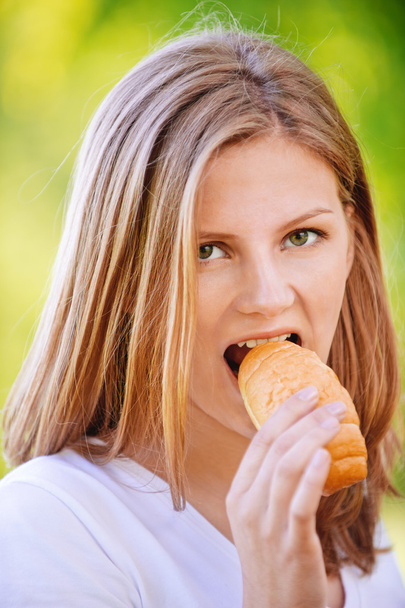 Portrait of young woman eating bun - Photo, Image