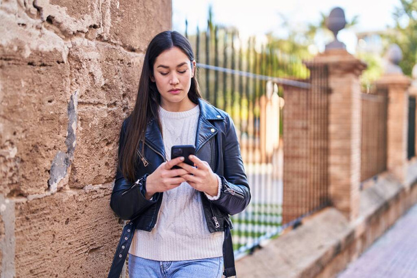 Nuori nainen käyttää älypuhelinta kadulla
 - Valokuva, kuva