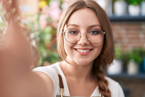 Jovem loira florista sorrindo confiante fazer selfie por câmera na florista - Foto, Imagem