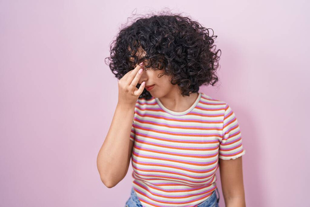 Giovane donna del Medio Oriente in piedi su sfondo rosa stanco sfregamento naso e gli occhi sensazione di stanchezza e mal di testa. concetto di stress e frustrazione.  - Foto, immagini
