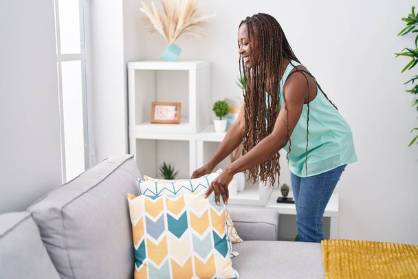 African american woman smiling confident organize sofa at home - Foto, afbeelding