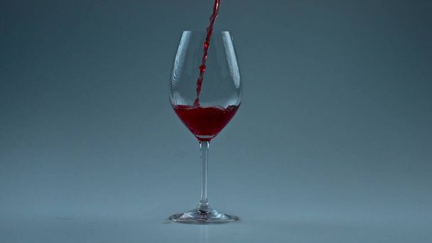 Sprankelende wijn jet gieten glas close-up. Fizzy alcohol vloeistof vullen schone vat slow motion. Verfrissende rode drank spetterend in wijnglas witte achtergrond. Luxe elegantie tipple concept  - Foto, afbeelding