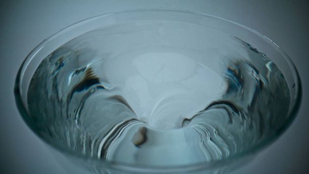 Primer plano aqua hielo haciendo embudo dentro de cristalería. Cóctel transparente girando en recipiente. Girando agua fría en tubo de vidrio. Recipiente de bebida fresca con tornado líquido giratorio super cámara lenta - Foto, Imagen