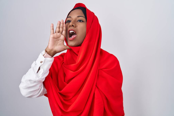 Mladá arabka na sobě tradiční islámský hidžáb šátek křičí a křičí hlasitě na stranu s rukou na ústech. komunikační koncept.  - Fotografie, Obrázek