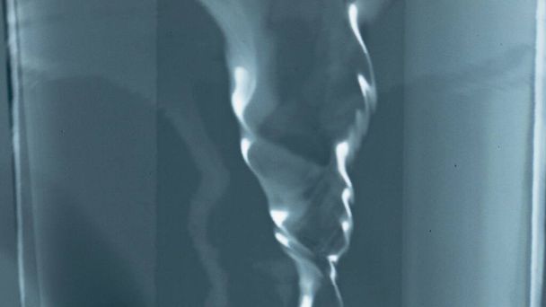 Φιλτραρισμένο aqua περιστρεφόμενο εσωτερικό γυάλινο δοχείο closeup. Κοκτέιλ πάγου που περιστρέφονται σε διαφανή γυάλινη μακροεντολή. Καθαρίστε κρύο νερό αργή κίνηση. Αναζωογονητικό αεριωθούμενο ποτό. Οικολογικό ποτό  - Φωτογραφία, εικόνα