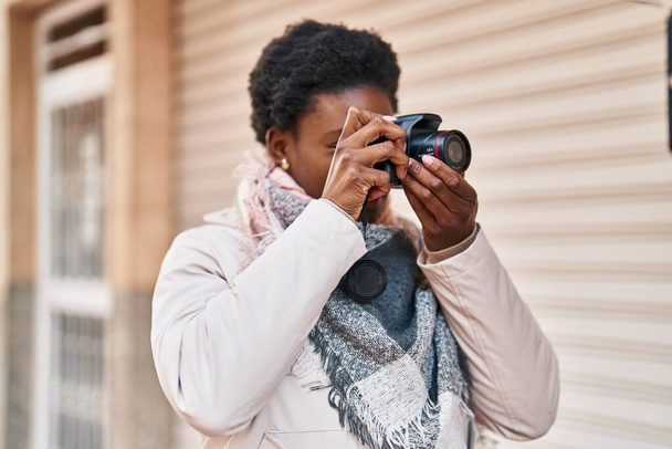 Afroamerikanerin lächelt selbstbewusst mit professioneller Kamera auf der Straße - Foto, Bild
