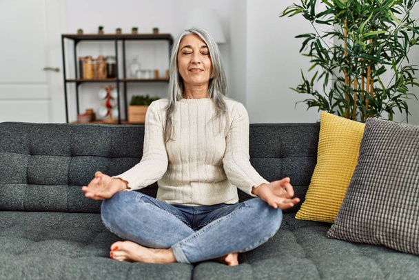 Жінка середнього віку сіро-волохата посміхається впевнено займається вправами йоги вдома
 - Фото, зображення