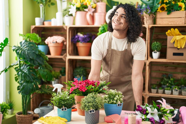 Jeune homme latin fleuriste souriant confiant debout à la boutique de fleurs - Photo, image