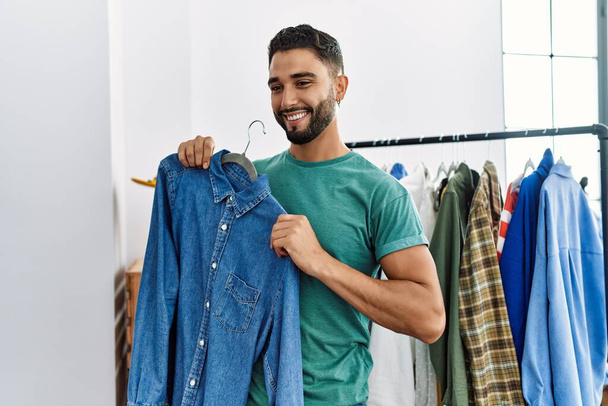 Nuori arabi mies asiakas hymyilee luottavainen ostoksia vaatekauppa - Valokuva, kuva