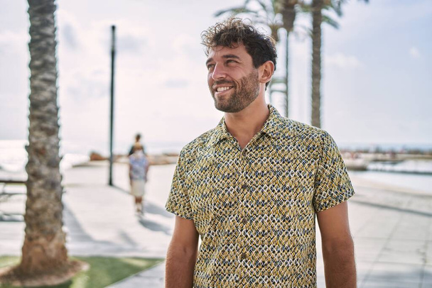 Молодой латиноамериканец уверенно улыбается, идя к морю - Фото, изображение