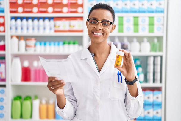 Afrikkalainen amerikkalainen nainen apteekissa pillerit pullo käsittelyssä reseptiä apteekissa - Valokuva, kuva