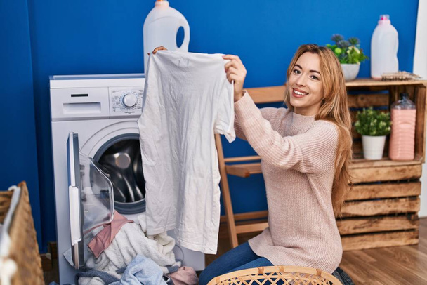Νεαρή γυναίκα που κρατά t πουκάμισο πλύσιμο ρούχα στο πλυσταριό - Φωτογραφία, εικόνα