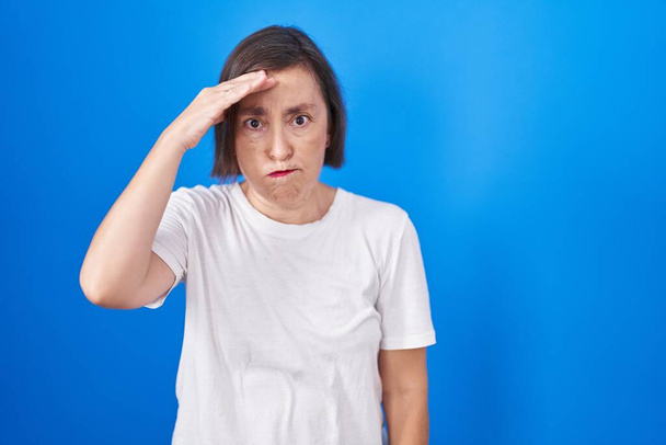 Middle age hispanic woman standing over blue background worried and stressed about a problem with hand on forehead, nervous and anxious for crisis  - Fotoğraf, Görsel