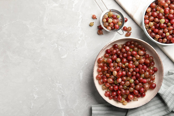 Ripe gooseberries on light grey marble table, flat lay. Space for text - Фото, изображение