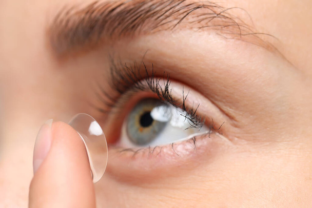 Woman putting in contact lens, closeup view - Foto, afbeelding