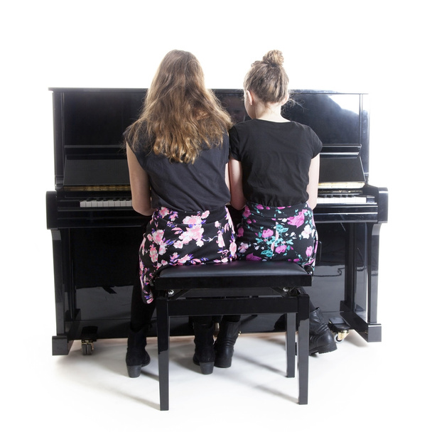 δύο έφηβες και μαύρο πιάνο σε όρθια θέση - Φωτογραφία, εικόνα