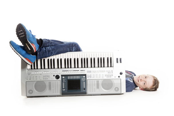 dospívající chlapec ležící za klávesnice ve studiu - Fotografie, Obrázek