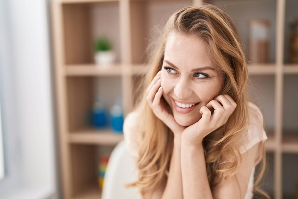 Young blonde woman smiling confident sitting on table at home - Foto, immagini