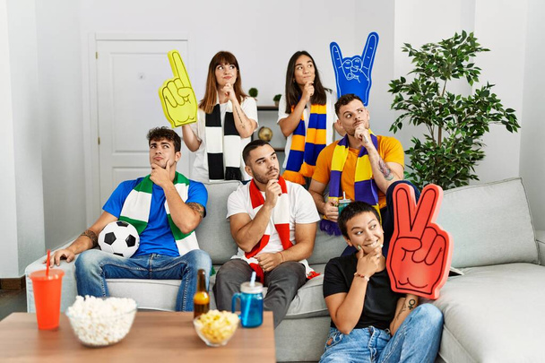 Grupo de personas hooligan fútbol animando juego cara seria pensando en la pregunta con la mano en la barbilla, reflexivo acerca de la idea confusa  - Foto, imagen